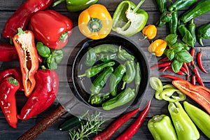 a colorful assortment of peppers, hot peppers and chili, decorated with various assesoires on a wooden table.