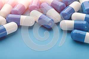 Colorful assortment of pills and capsules on  blue background, close-up.