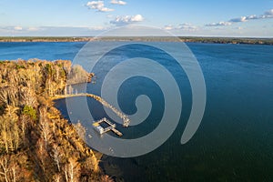 Colorful autumn forest with trees on the shore of a blue lake - top aerial view
