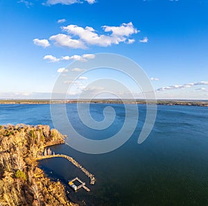 Colorful autumn forest with trees on the shore of a blue lake - top aerial view