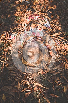 Colorful autumn and happy child lying in orange, yellow leaves