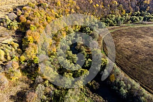 A colorful autumn landscape from the air, a view of the river flowing between the forest and the field