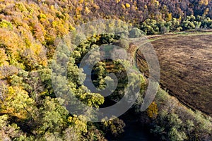 A colorful autumn landscape from the air, a view of the river flowing between the forest and the field