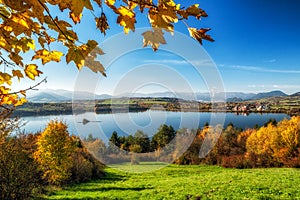 Farebná jesenná krajina s jazerom, žltými stromami a horami na pozadí