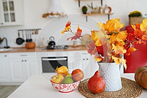 Colorful autumn still-life on a kitchen table. Pumpkin, bouquet of maple leaves and apples