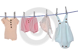 Colorful baby clothes drying on laundry line against white background