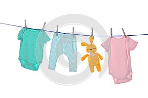 Colorful baby clothes and toy drying on laundry line against background