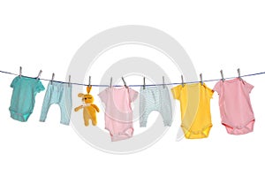 Colorful baby clothes and toy drying on laundry line against background