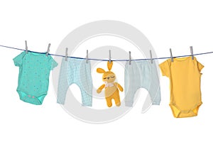 Colorful baby clothes and toy drying on laundry line against background