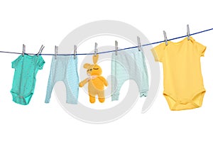 Colorful baby clothes and toy drying on laundry line against background