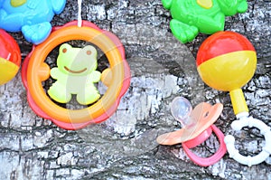 A colorful baby rattle on a wooden background baby`s dummy