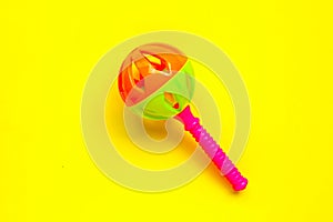 Colorful baby rattle on yellow background