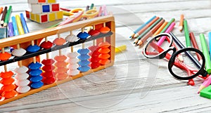 Colorful back to school supplies double border over white table. Mental arithmetic scores abacus. Space for text.