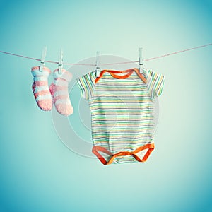 Colorful background for baby girl with two pink socks and body suit with copy space.