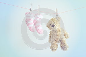Colorful background for baby girl with two pink socks and teddy bear with copy space.