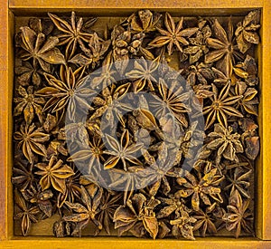 Colorful background dry starry anise crumple in a wooden lot of spices in a wooden frame base