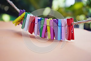 Colorful background of wooden clips on rope on green light bokeh and soft orange background. Colorful objects backgrounds.