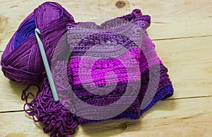 Colorful ball of wool and piece of woven winter garment with crochet needle or hook against light background. copy space