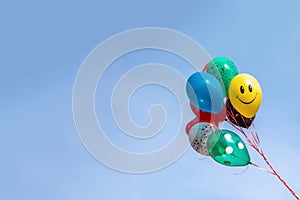 Colorful balloon floating in mid air against a bright blue sky.