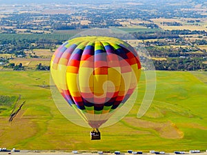 Colorful Balloon flyng over a green field photo