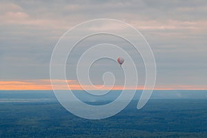 Colorful balloon high above the ground in the sky at sunset in fog