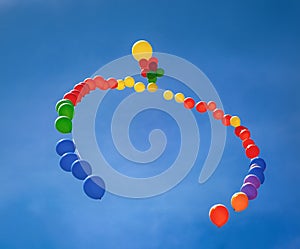Colorful balloons in an arc floating in a blue sky with clouds