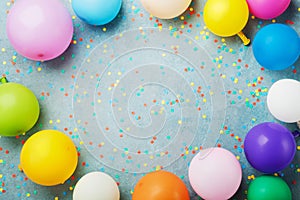 Colorful balloons and confetti on turquoise table top view. Birthday, holiday or party background. Flat lay style.