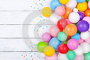 Colorful balloons and confetti on white table top view. Festive or party background. Flat lay. Birthday greeting card