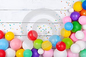 Colorful balloons and confetti on white table top view. Festive or party background. Flat lay. Birthday greeting card