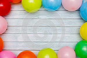 Colorful balloons and confetti on wooden table top view. Festive or party background. Flat lay style. Birthday greeting card.