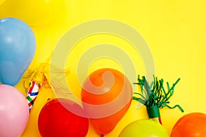 Colorful balloons and confetti on yellow table top view. Festive or party background. Flat lay style. Birthday greeting card.