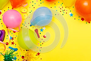 Colorful balloons and confetti on yellow table top view. Festive or party background. Flat lay style. Birthday greeting card.