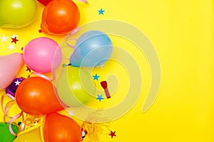 Colorful balloons and confetti on yellow table top view. Festive or party background. Flat lay style. Birthday greeting card.