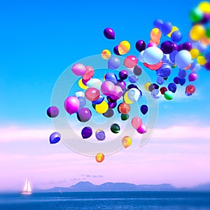 Colorful balloons drifting over the calm blue sea.