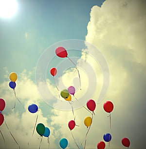 colorful balloons flying in the blue sky with antiqued effect