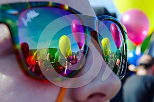 colorful balloons reflected in sunglasses of a spectator at the festival