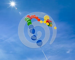 Colorful balloons in a row floating in a blue sky with clouds