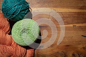 Colorful balls and skeins of yarn on an old wood background, creative copy space, knit and crochet needle arts theme