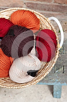 Colorful balls of wool yarn in a basket on the rustic background