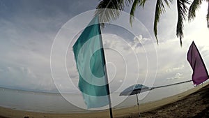 Colorful banner flags and Umbrella Parasol line on tropical empty sandy beach.