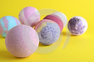 Colorful bath bombs on yellow background, closeup