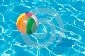 Colorful beach ball floating in pool
