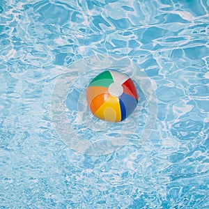 A colorful beach ball floating on the swimming pool.