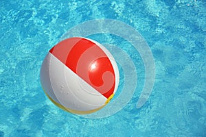 Colorful beach ball floating in swimming pool. Space for text