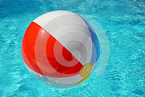 Colorful beach ball floating in swimming pool. Space for text