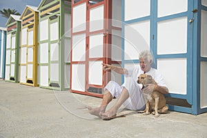Colorful beach huts and senior man with dog