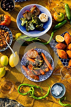 Colorful beach picnic with vegetables dishes, lemons and peppers