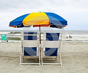 Colorful beach umbrella and blue chairs