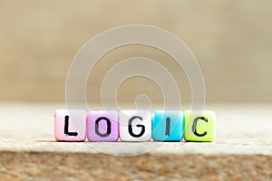 Colorful bead with letter in word logic on wood background