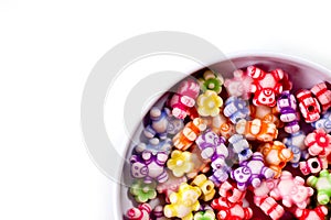 Colorful beads in the form of bears and flowers for making jewelry shot close-up on a white background